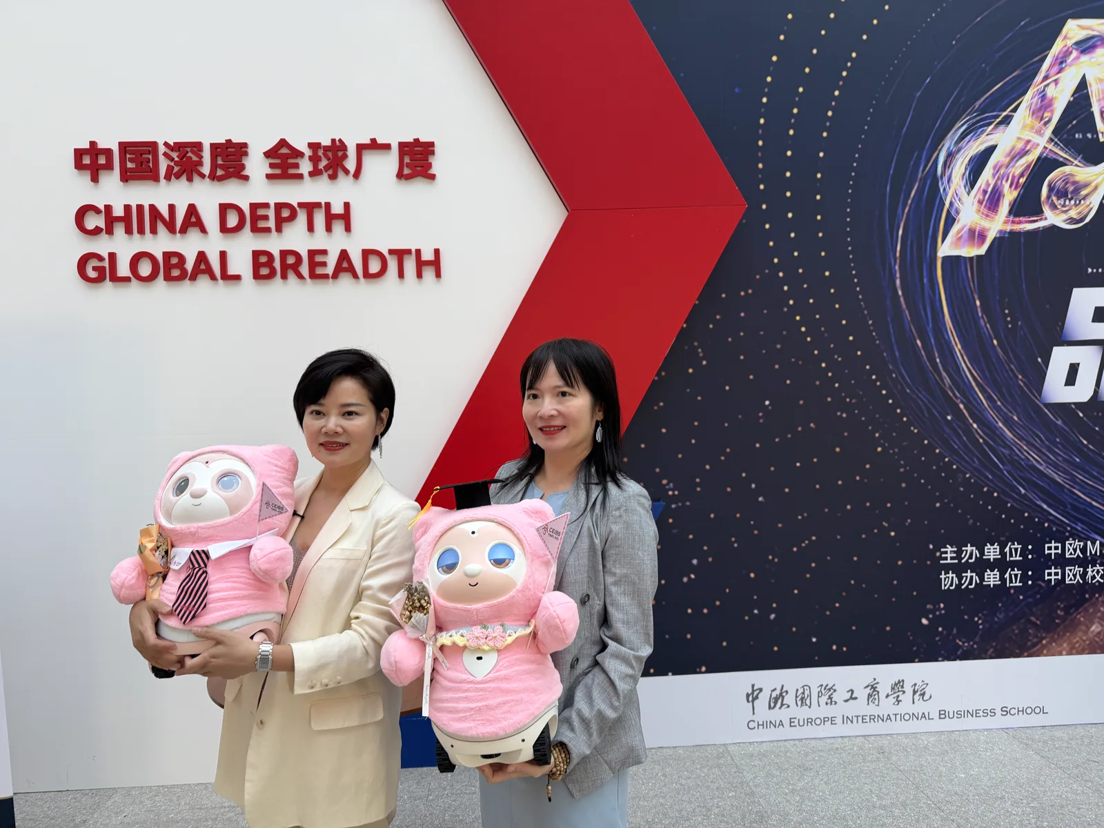 两位来宾在中欧营销论坛现场分别抱着粉色康康合影