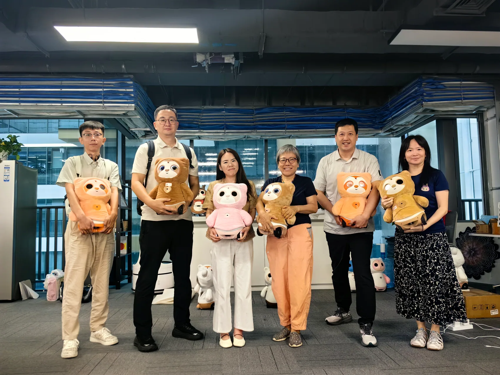 六人在心忆科技办公室抱着不同颜色的康康合影
